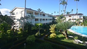 Ein Hotel mit Pool, umgeben von Palmen und gepflegten Gärten.