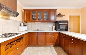 A kitchen with wooden cabinets, a built-in oven, a microwave, and a gas stove. - Cozy home in Donji Humac (Donji Humac)