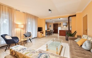 A living room with a sofa, armchair, and coffee table, a dining area with chairs, and a kitchen in the background. - Cozy home in Donji Humac (Donji Humac)