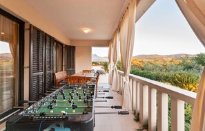 Una mesa de futbolín en un balcón con vistas a un paisaje montañoso.