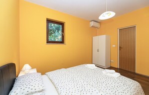 A room with a bed, a wardrobe, a window with a view of trees, and an air conditioning unit. - Cozy home in Donji Humac (Donji Humac)