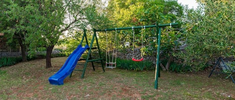 A playground with a blue slide and swings.
