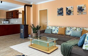 A living room with a sofa, a glass coffee table, a kitchen area, and a door. - Cozy home in Donji Humac (Donji Humac)