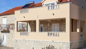 A two-story building with a stone facade, a red-tiled roof, and a balcony with a metal railing. - 2 bedroom gorgeous apartment in Donji Humac (Donji Humac)