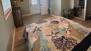 Ein Schlafzimmer mit Bett, Deckenventilator und einer Tür zu einem anderen Raum.