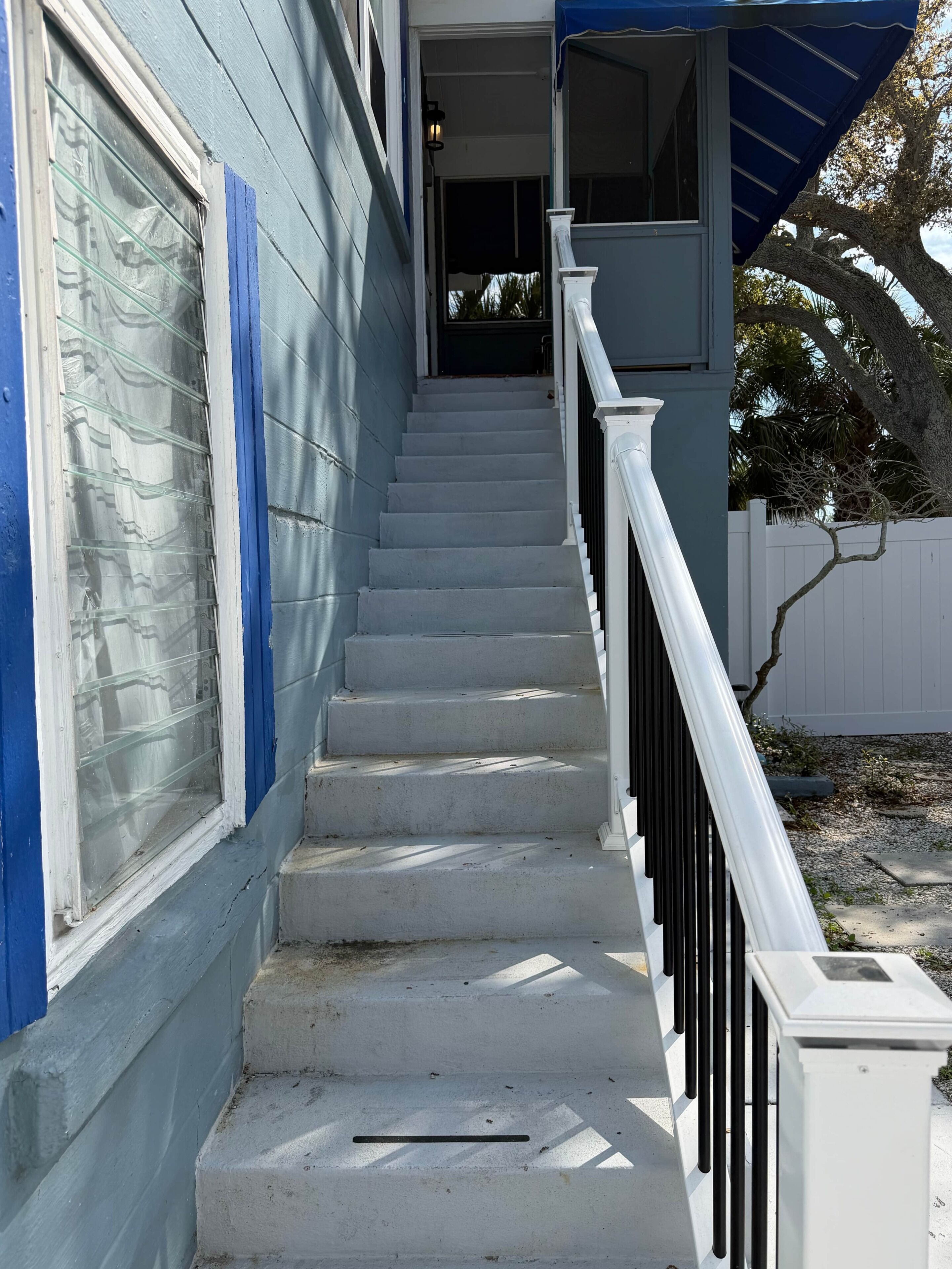 A staircase leading to a building entrance with a blue exterior and a white railing.