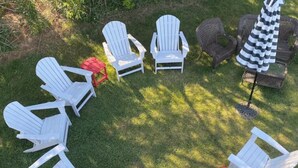 Disposición circular de asientos al aire libre con sillas y una mesa, rodeado de césped.