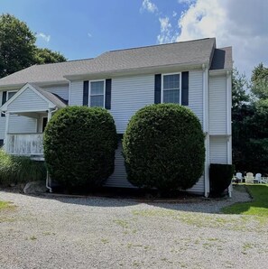 A two-story house with a porch, a gravel driveway, and two well-maintained bushes. - Oasis in the Narragansett Pier. Family retreat home Comfortably sleeps 12 (Narragansett)