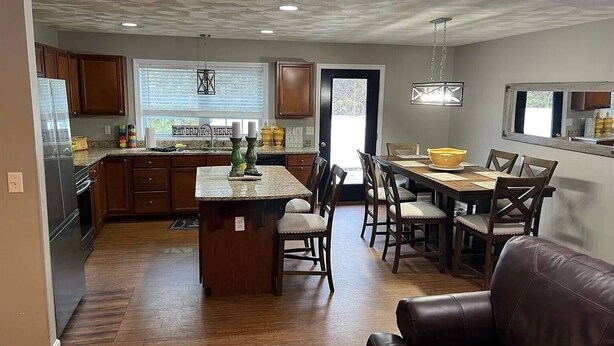 Una cocina amplia con una isla central, armarios de madera y un comedor con mesa y sillas.