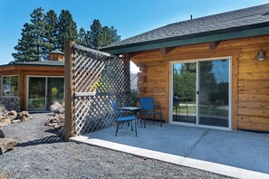Eine Holzhütte mit einer Terrasse, zwei Stühlen und einer Schiebetür.