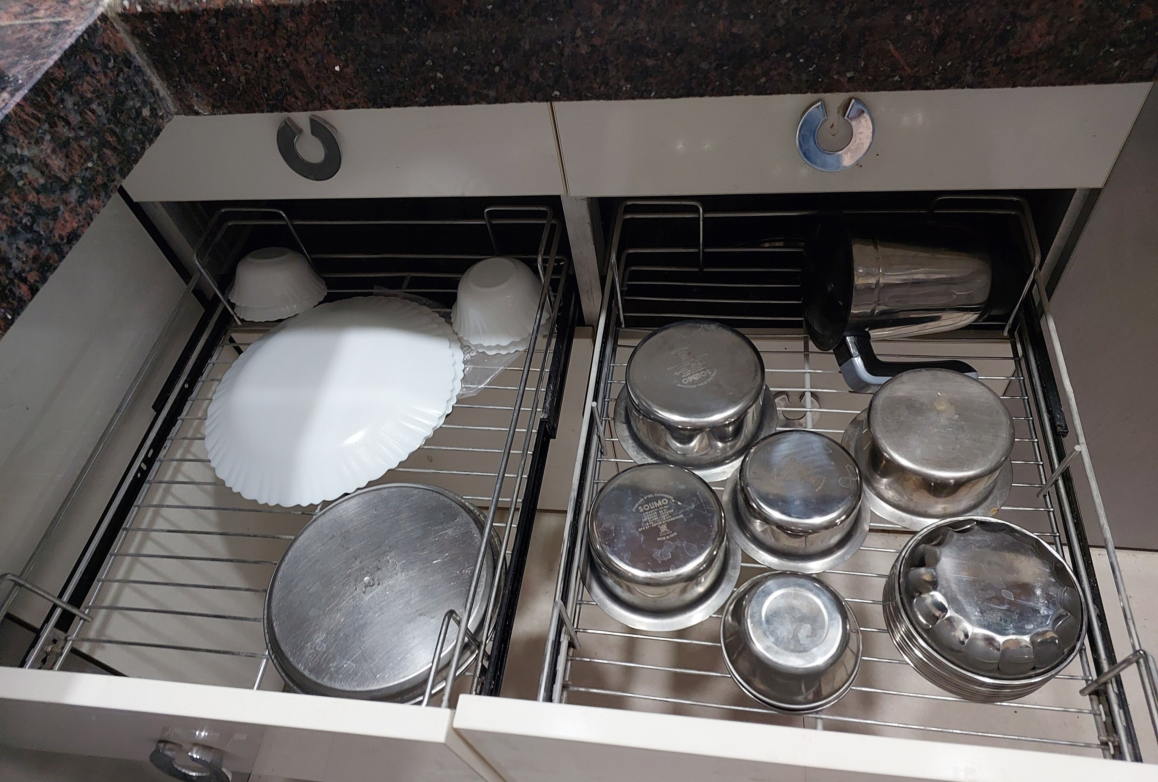 A kitchen drawer with various cookware and dishes.