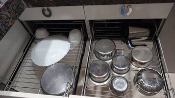 A kitchen drawer with various cookware and dishes.