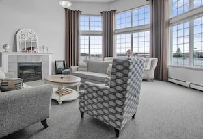Un salon moderne avec une cheminée, de grandes fenêtres et un fauteuil à motifs.