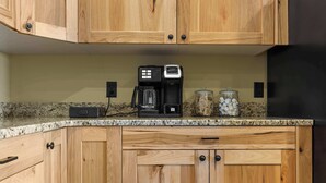A kitchen with wooden cabinets, a coffee maker, and a jar of sugar packets. - Lake Front | Pontoon | Private Beach | Hot Tub (New Lisbon)