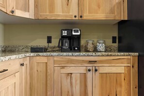 A kitchen with wooden cabinets, a coffee maker, and a jar of sugar packets.