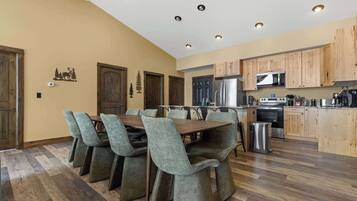 A modern kitchen with wooden cabinets, stainless steel appliances, and a dining area with a wooden table and upholstered chairs.