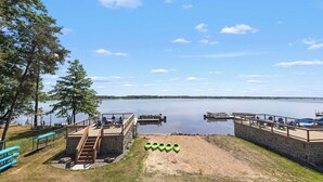 A lakeside dock with a stone staircase leading to a deck, kayaks, and a clear view of the lake. - Lake Front | Pontoon | Private Beach | Hot Tub (New Lisbon)