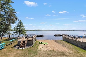 A lakeside dock with a stone staircase leading to a deck, kayaks, and a clear view of the lake.