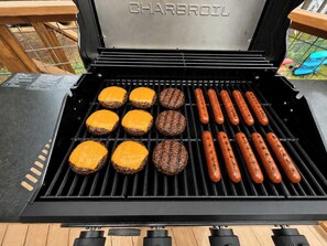 Ein Charbroil Grill mit Bratburgern und Würstchen, die darauf gegrillt werden.