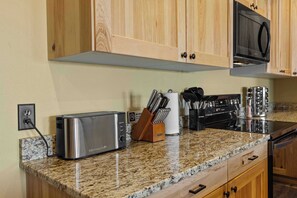 A kitchen with a built-in toaster, a stove, and a microwave. There is a knife block and a paper towel holder on the counter.