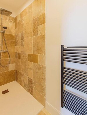 Un baño con ducha, paredes de azulejos y un perchero.