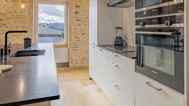 A modern kitchen with a stone wall, a large window, and built-in appliances.
