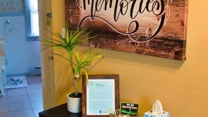 Un comptoir d’accueil avec une lettre de bienvenue encadrée, une petite plante, un bol en verre contenant une carte et un sac bleu à motifs.