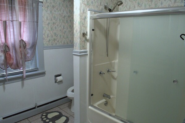 A bathroom with a glass-enclosed shower, a toilet, and a window with blinds. - The Comfy Nest, Minutes to Waterparks, Outlets, Casino (Tannersville)