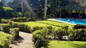 Ein Weg, der zu einem Pool inmitten üppiger Vegetation und Palmen führt.