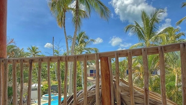Ein Balkon mit Frühstückstisch, Blick auf Pool und Palmen.