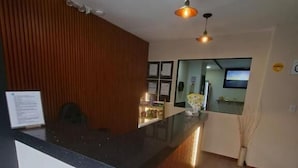 Zona d'entrada amb un mur de panells de fusta, una recepció negra i il·luminació penjant.