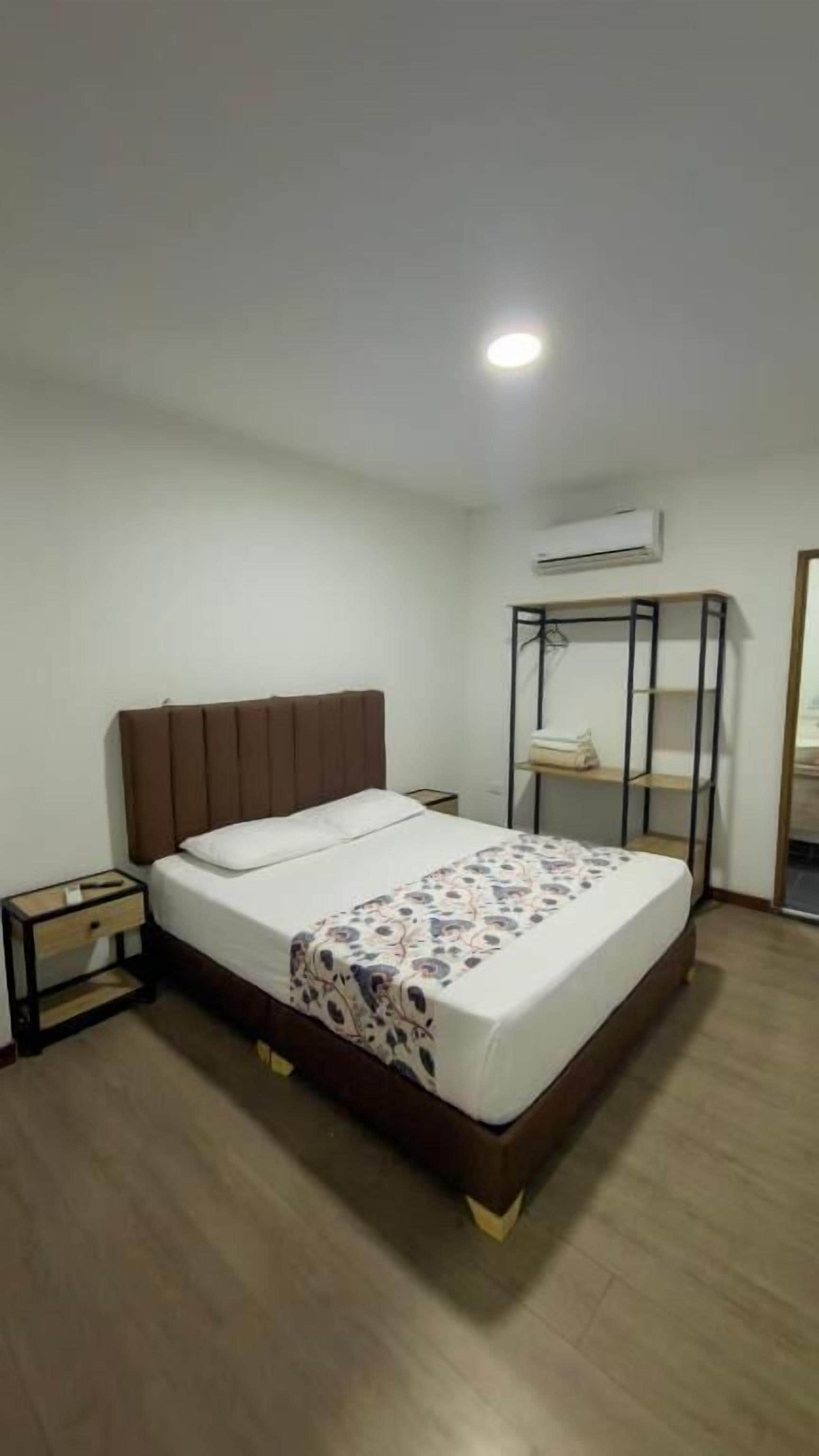 Un dormitorio con cama, mesita de noche, armario y aire acondicionado.