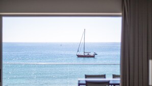 A room with a view of the sea, a sailboat, and outdoor seating. - Sesimbra Ocean Terrace (Sesimbra)