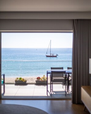 A room with a view of the sea, a sailboat, and outdoor seating. - Sesimbra Ocean Terrace (Sesimbra)