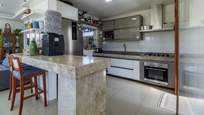 A modern kitchen with a marble island, built-in oven, and stainless steel appliances.
