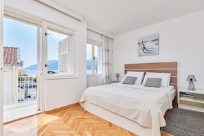 Une chambre à coucher avec un lit, une table de chevet, une lampe et une vue sur l’extérieur.