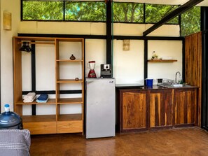 Eine kleine Küche mit integriertem Kühlschrank, einer Kaffeemaschine und einem Spülbecken.