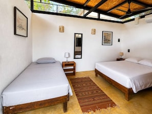 A room with two beds, a small table, a mirror, and a window. - Loft, cama Queen, cama individual, cocina completa (Cuatunalco)
