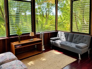 A room with a grey sofa, a wooden coffee table, a lamp, and a bookshelf.