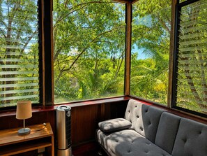 A room with a large window, a sofa, a lamp, and a heater. - Bungalow doble, cama Queen, cama individual y terraza exterior cocina completa y sofa cama (Cuatunalco)