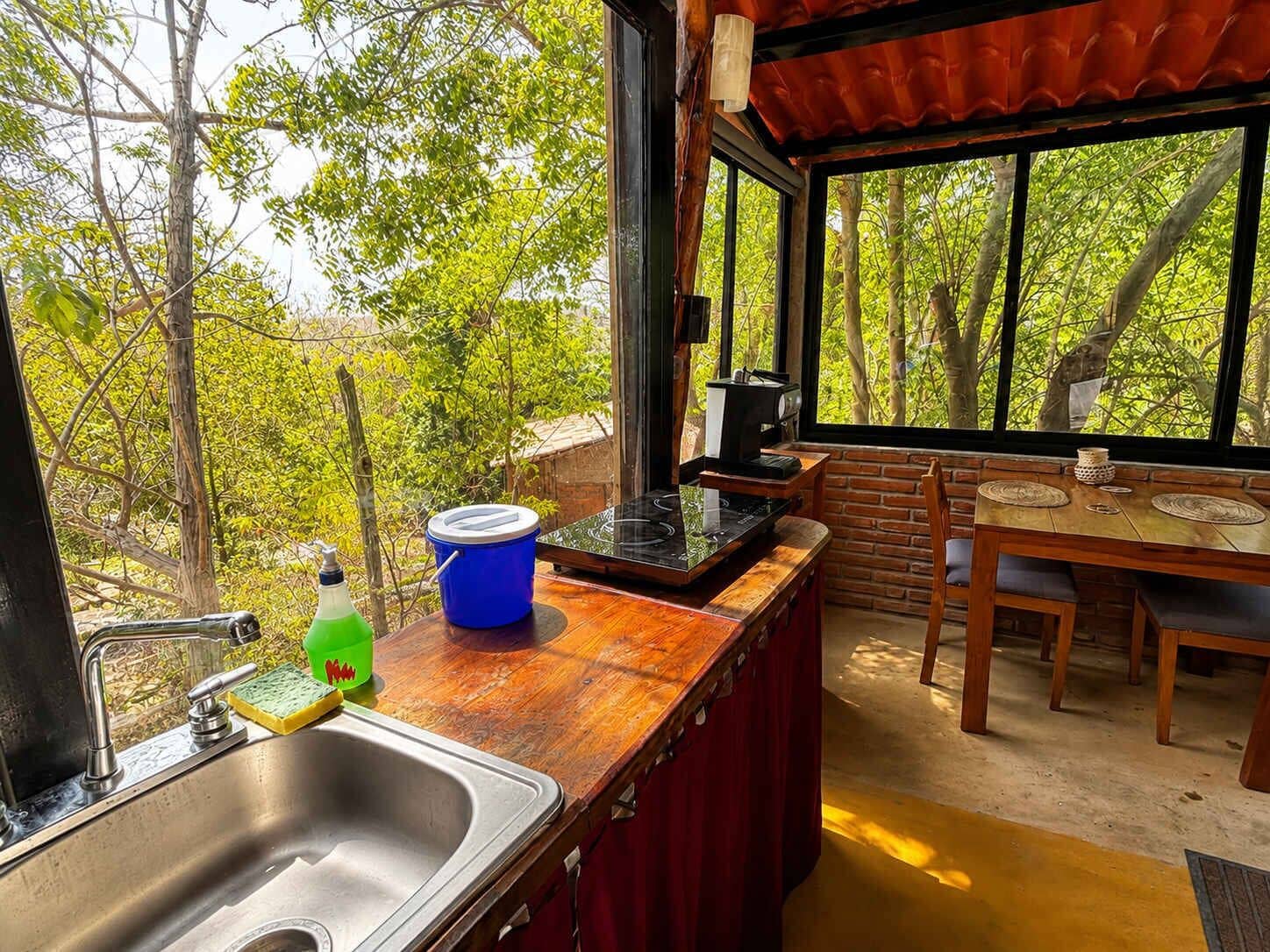 A kitchen with a sink, stove, and dining area with a table and chairs.