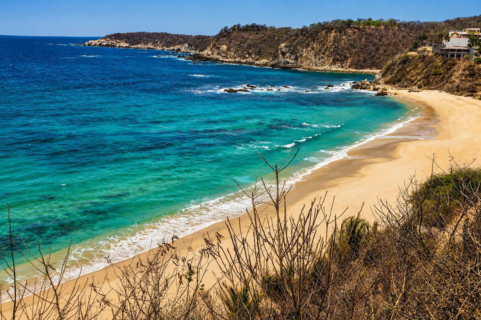 Eine Küstenlandschaft mit Sandstrand, klarem türkisblauem Wasser und steilen Felsen.