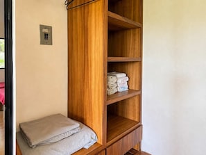 Una prestatgeria de fusta amb tovalloles doblades i una presa corrent a la paret.