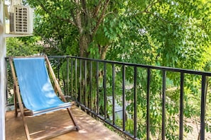 A balcony with a blue cloth, a metal railing, and trees in the background. - Valeria Bungalow doble, cama Queen, cocina completa y sofa cama (Cuatunalco)