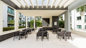 Une terrasse extérieure avec des tables et des chaises, un mur en pierre et une vue sur un immeuble doté de balcons.