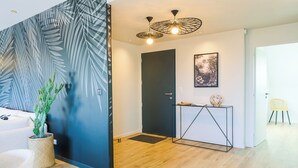 Een modern interieur met een houten vloer, een donkere deur, een console tafel met een wereldbol en een cactus.