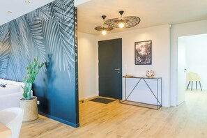 Ein modernes Interieur mit Holzboden, einer dunklen Tür, einem Konsolentisch mit Globus und einer Kakteenpflanze.