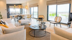 Een moderne hotelkamer met een zithoek, grote ramen en uitzicht op zee.