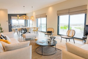 Ein modernes Hotelzimmer mit Essbereich, großen Fenstern und Blick auf das Meer.
