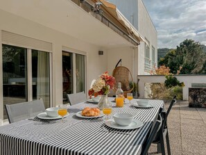 Un espace repas avec une nappe à rayures, des sièges en plein air et une vue sur le paysage environnant.